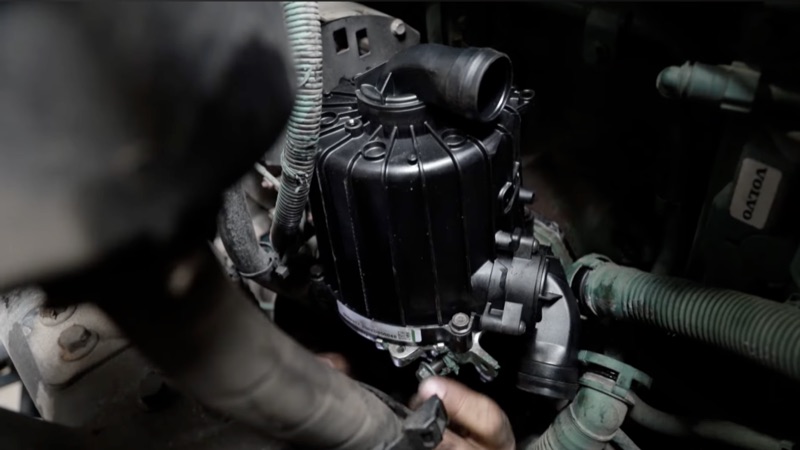 Technician replacing a fuel filter housing on a diesel engine